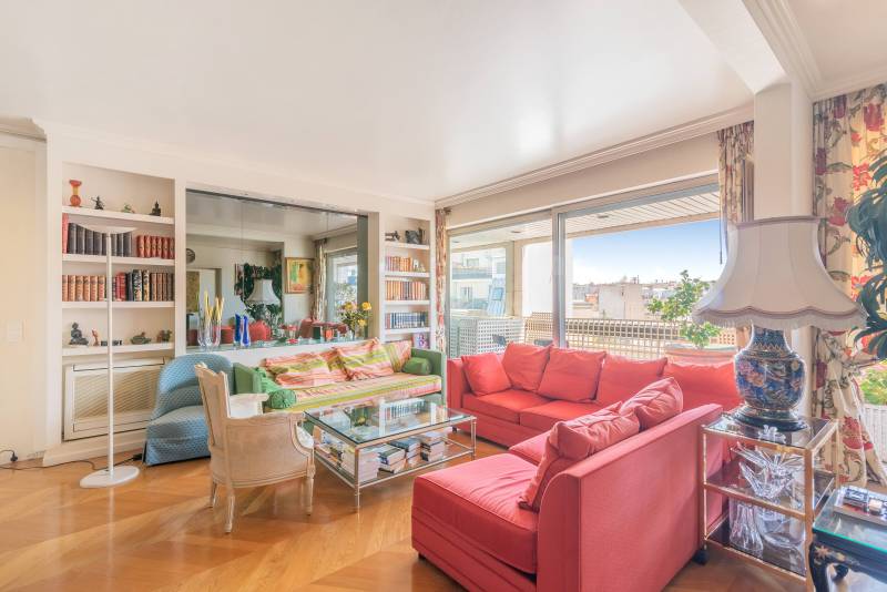 Salon lumineux modulable offrant une vue exceptionnelle sur Paris, élégamment présenté par notre agence immobilière Paris 6ème.