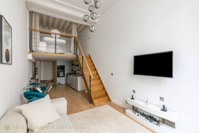 Séjour avec mezzanine offrant perspective aérienne, cuisine ouverte intégrée et volumes harmonieux, idéal pied-à-terre rive gauche parisien.