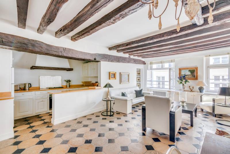 Salon lumineux réunissant espace détente, salle à manger et cuisine ouverte dans un cadre empreint de charme ancien au cœur du 6ème arrondissement.