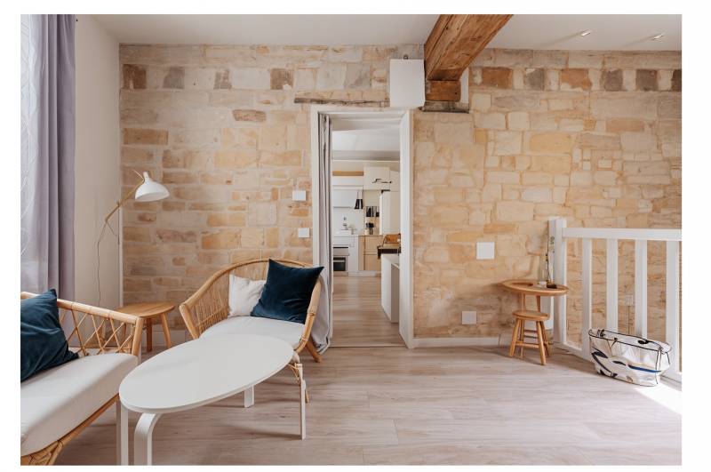 Salon au cachet ancien mêlant pierres apparentes, poutres et parquet, idéal pour amateurs d’authenticité rive gauche parisienne