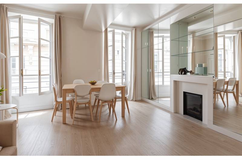 Espace salon, cheminée d’époque et parquet ancien soulignant le caractère unique de ce duplex parisien authentique